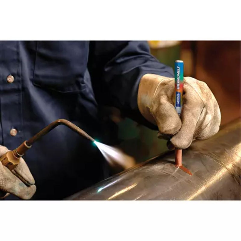 metal worker preheating steel while holding heat stik indicator to check temperature