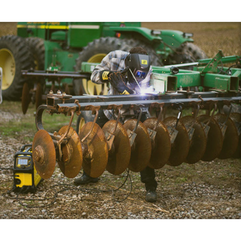 Action shot of a welder performing a stick weld on agricultural equipment using an esab rebel EMP 215ic welder