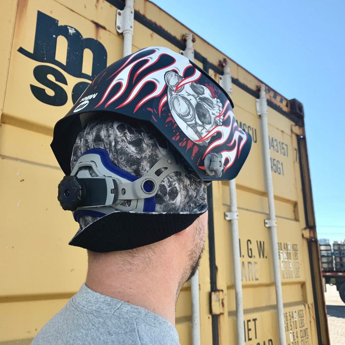 a model wearing a miller ghost skull beanie underneath a miller welding helmet