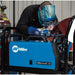 man mig welding with a millermatic 211 while wearing miler welding helmet and miller welding gloves