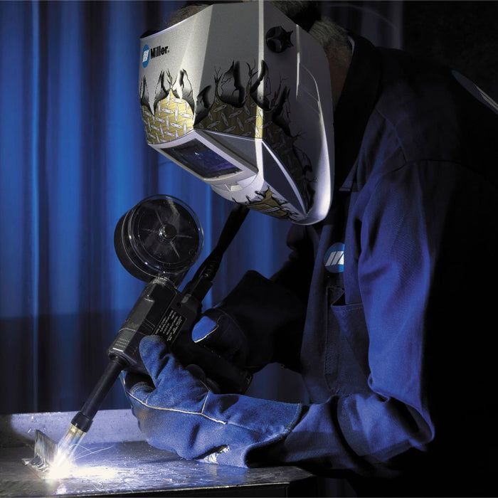 action shot of a welder welding aluminum using the miller spoolmatic 30A spoolgun wearing a blue miller welding jacket