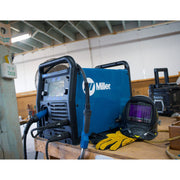 miller millermatic 255 on work bench with welding helmet and welding gloves